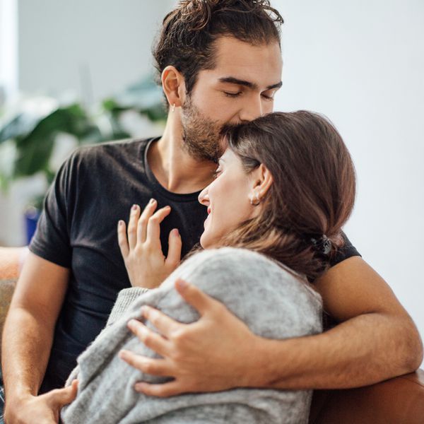 Young Couple Hugging on the Couch While Man Kissing Girlfriend on the Head