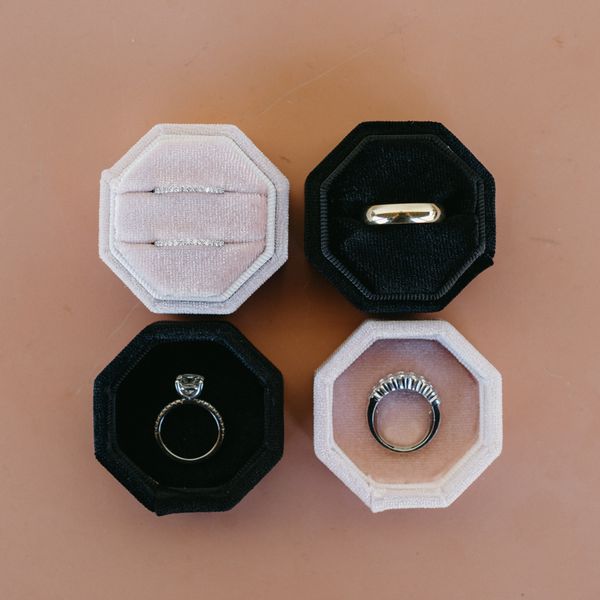 four wedding rings in individual ring boxes in contrasting black and blush colors