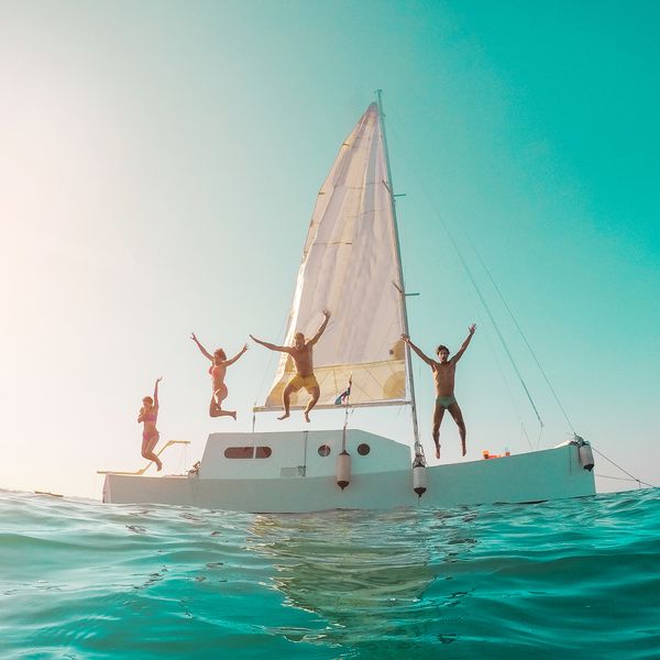 Friends jumping off a sailboat into the ocean at a bachelorette bachelor party