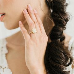 Woman holding her hand to her face wearing a diamond engagement ring