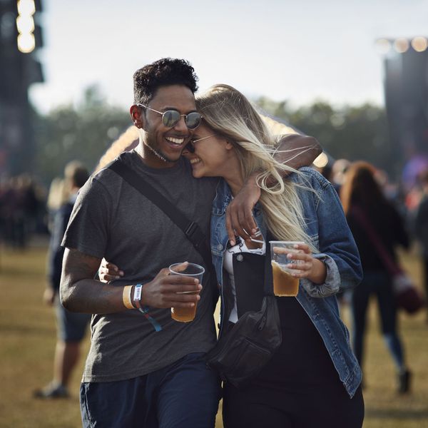 Man and Woman Holding Beer With Arms Around One Another Outside