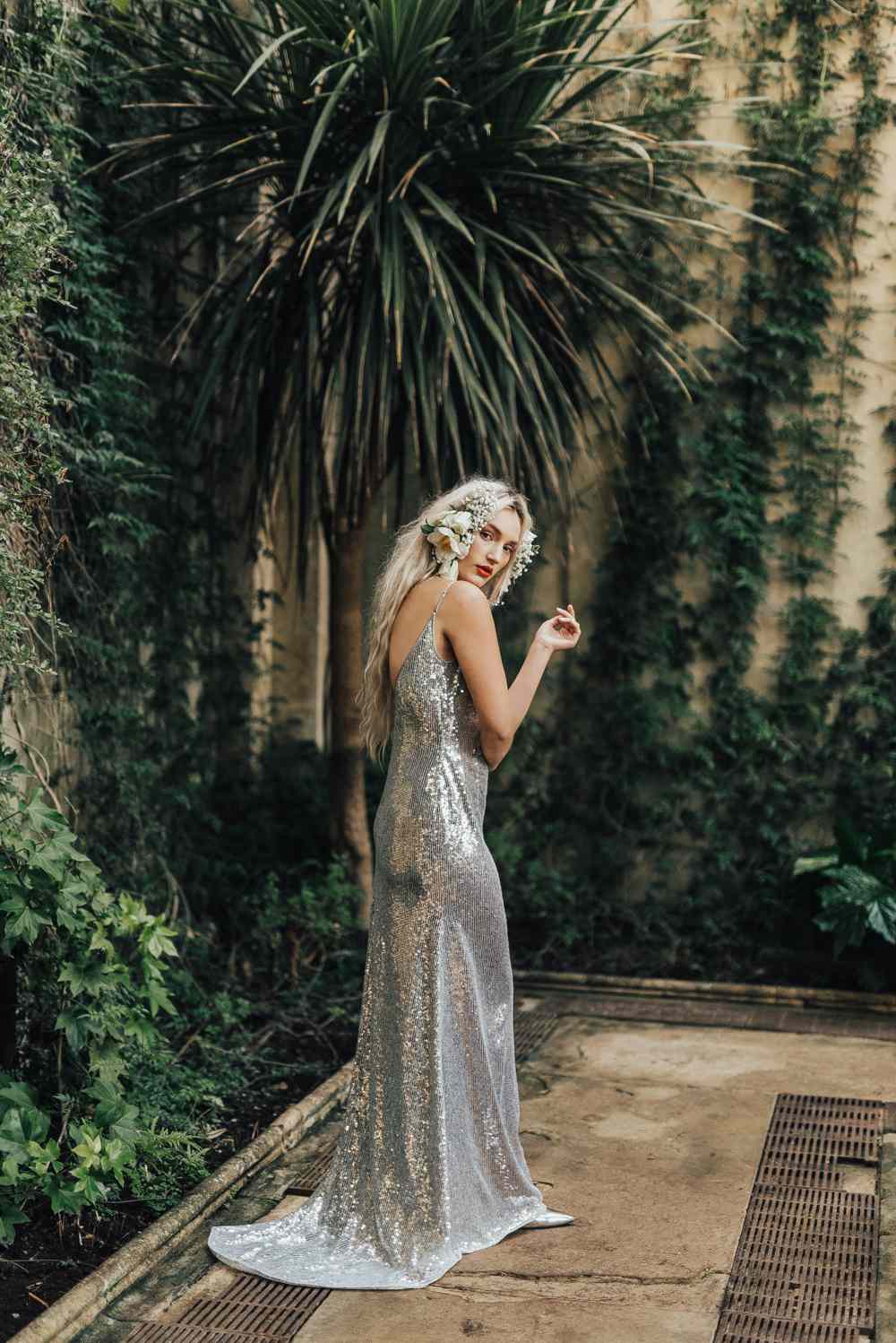 Model in a secret garden wearing a silver wedding gown with flowers in her hair