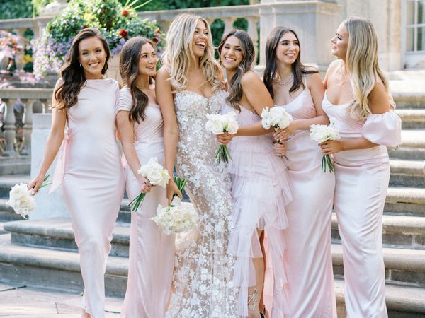 Bridesmaids in Baby Pink Satin Dresses Smiling With the Bride