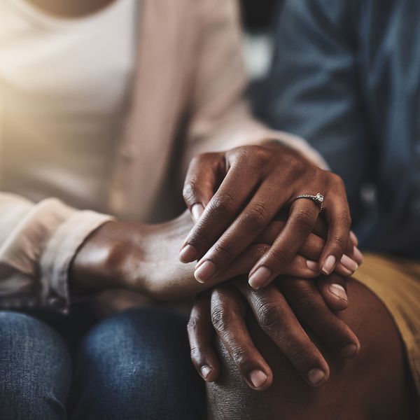 A couple in karmic relationship sits on the couch embracing hands