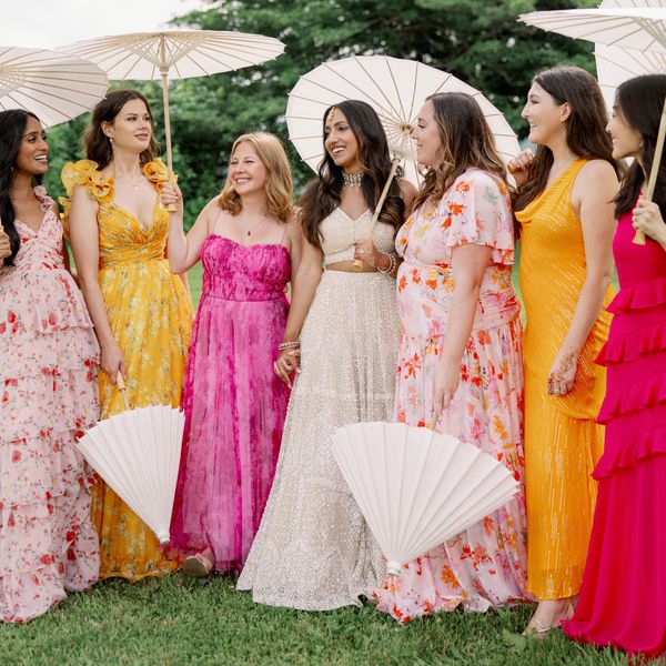 Indian Bride in Cream Lehenga With Bridesmaids in Pink, Orange, and Red Dresses Holding Parasols