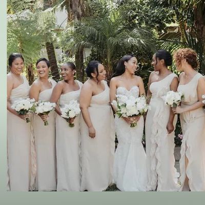 Brides standing with bridesmaids in front of palm trees