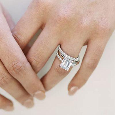 emerald-cut diamond engagement ring and eternity wedding band on a woman's finger 