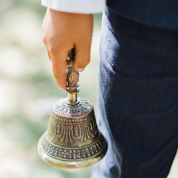 A boy holding a bell at a wedding.