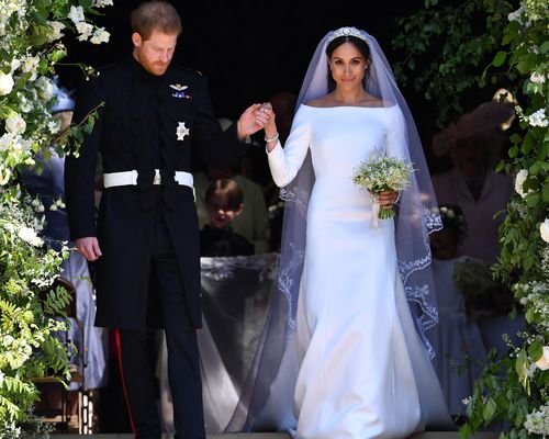 Meghan Markle wearing a Givenchy wedding gown, walking with Prince Harry on their wedding day in London in 2018.