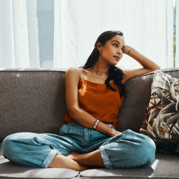 Shot of a young woman looking thoughtful while relaxing on the sofa at home