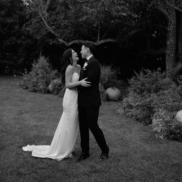 Black and White Portrait of Bride in Wedding Dress with Hair Down Posing with Groom in Tuxedo