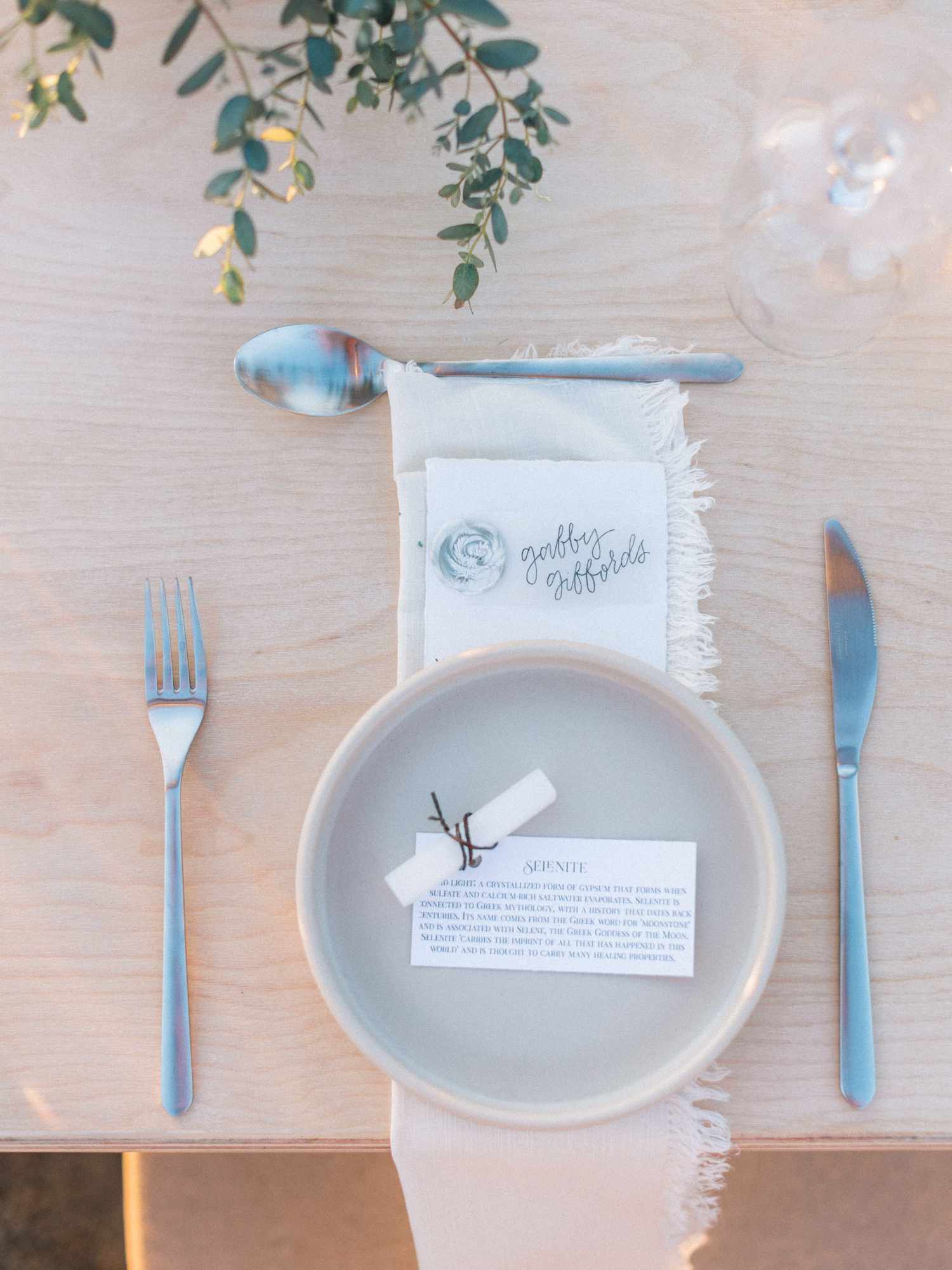 Wedding place card with gray plate, fringe linen napkin, and stone favor with card