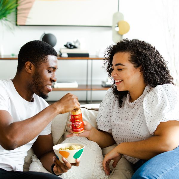 man and woman eating on couch at home