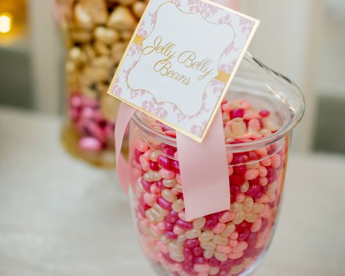 a jar of pink, red, and gold jelly beans at a wedding candy bar