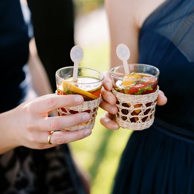 Signature wedding cocktails served in rattan cupholders at a wedding.