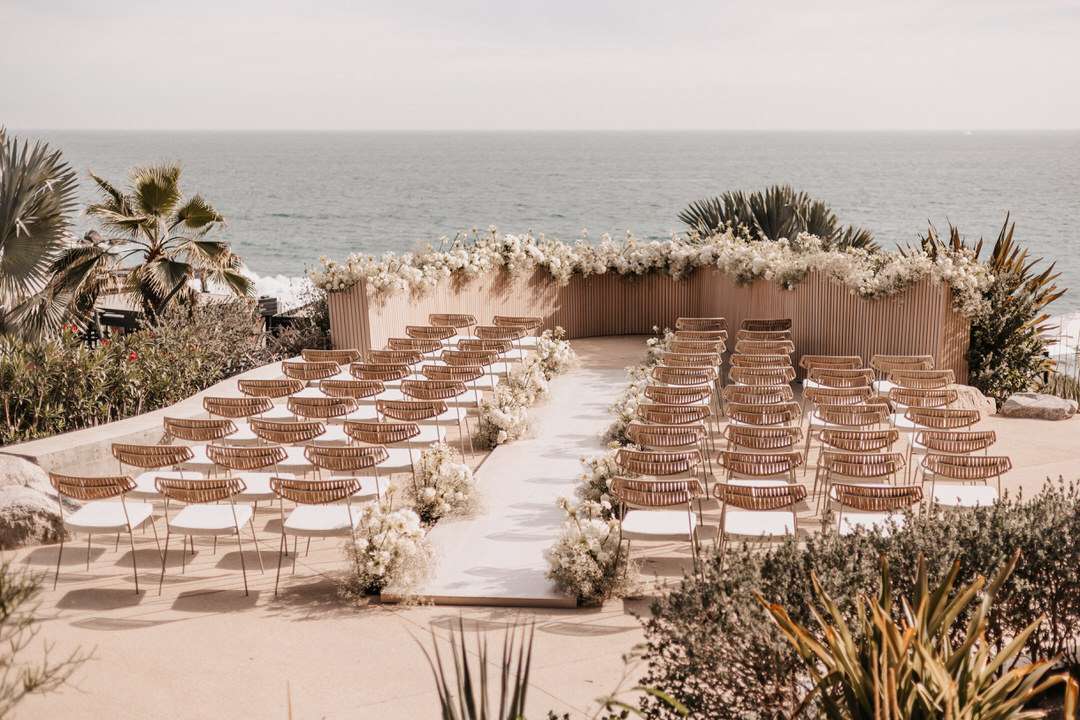 seaside wedding ceremony with wood details and wood and floral backdrop