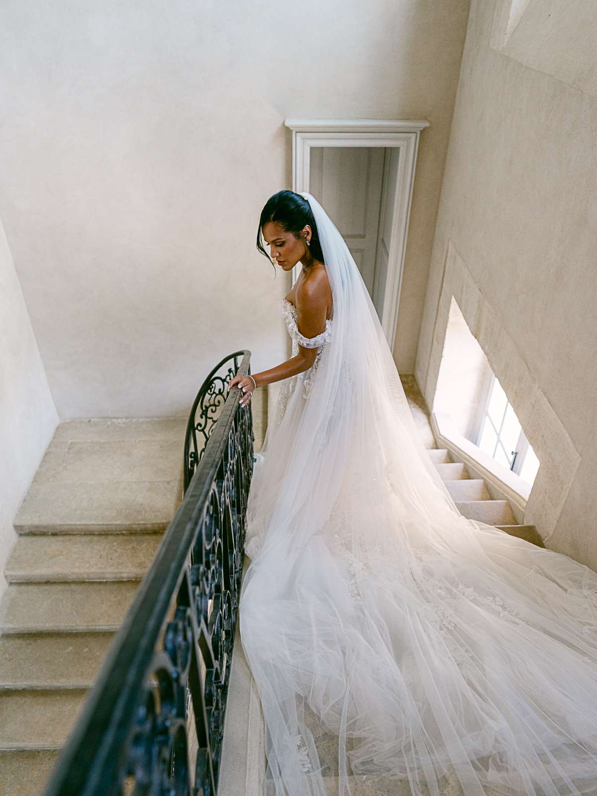 bride walking down stairs wearing a long tulle veil