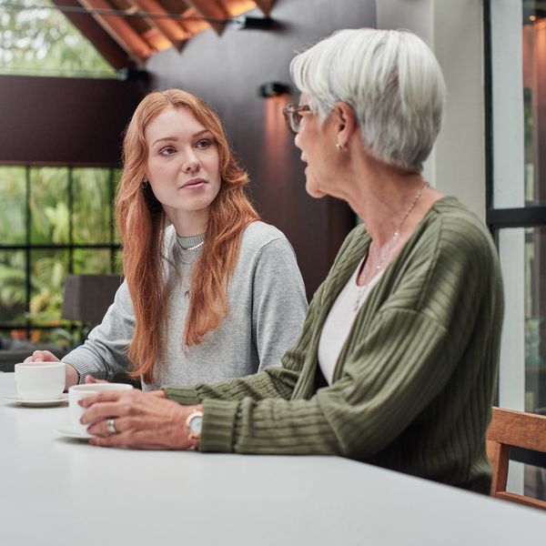 Young woman with red hair having a difficult conversation at home with her in-law wearing a green sweater.