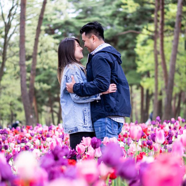 Man and Woman Looking at Each Other and Touching Foreheads in a Bed of Flowers