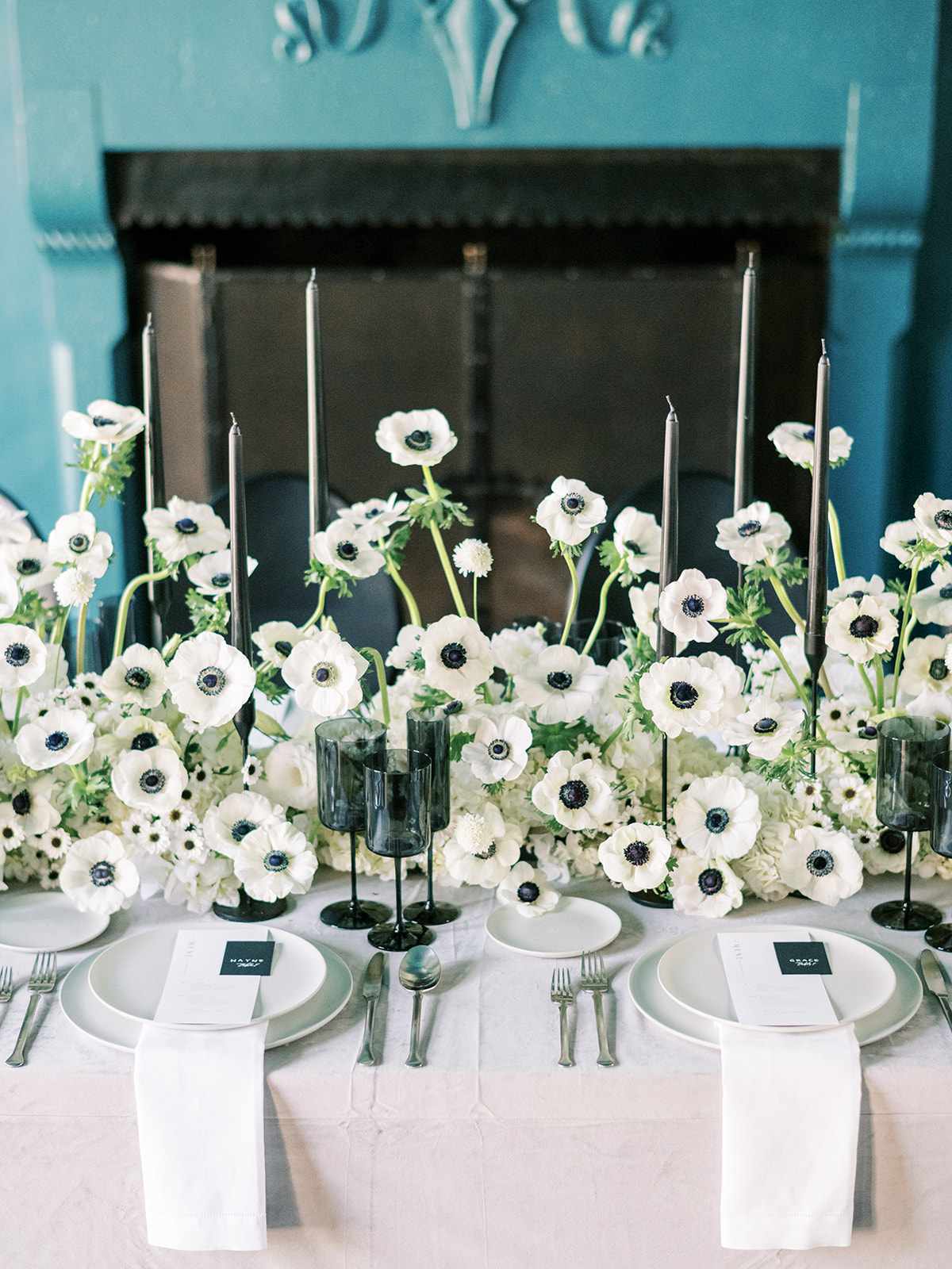 Wedding reception table with anemones, black taper candles, and black glassware