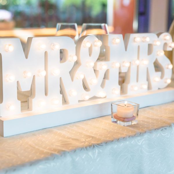 A white, lit-up Mr. and Mrs. sign at a wedding. 