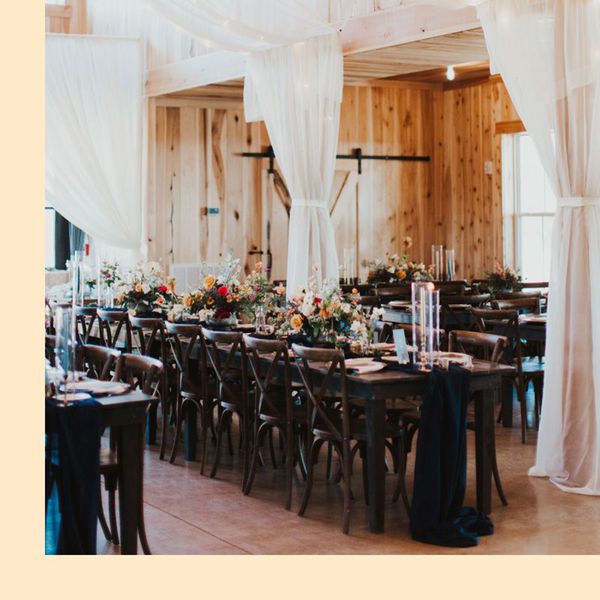 Dark Wood Wedding Reception Table With Black Runner, Red and Yellow Centerpieces, and Draping