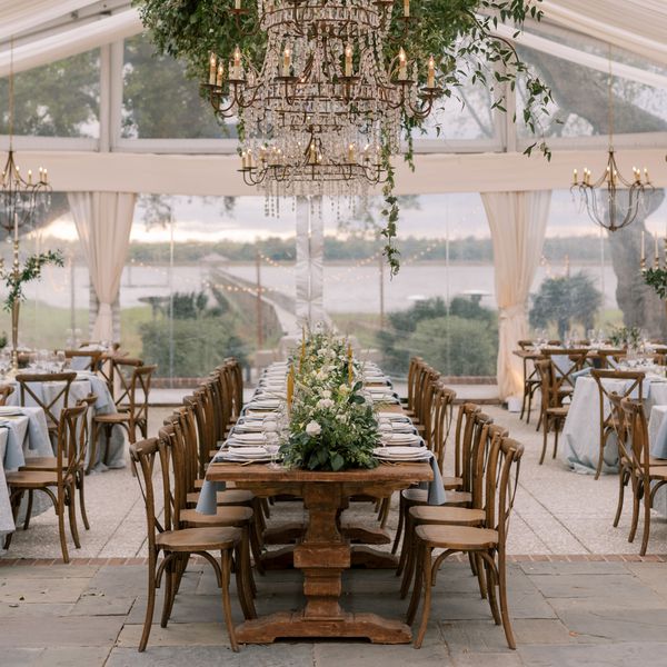 Head Table at a Wedding With Place Settings, Greenery, and Taper Candles, Surrounded by Round Tables