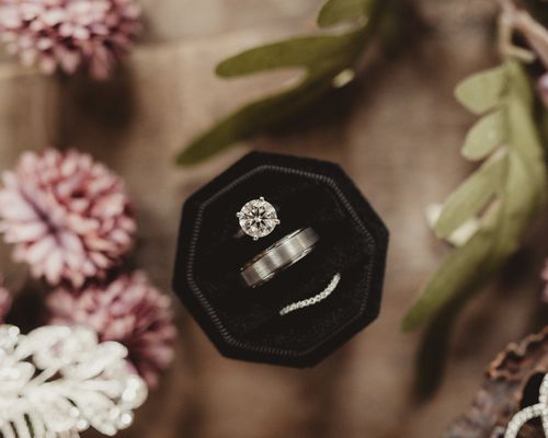 Round Diamond Engagement Ring Shown With Men's Wedding Band and Woman's Wedding Band in Black Ring Box