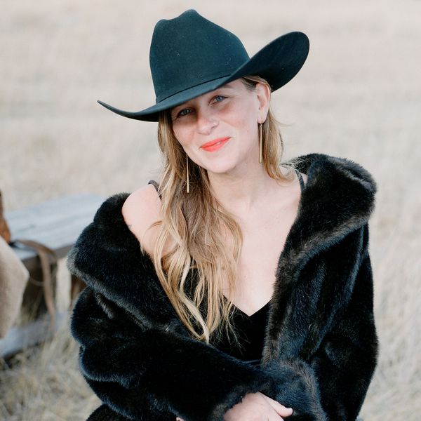 a wedding guest wearing a black cowboy hat and a black fur coat