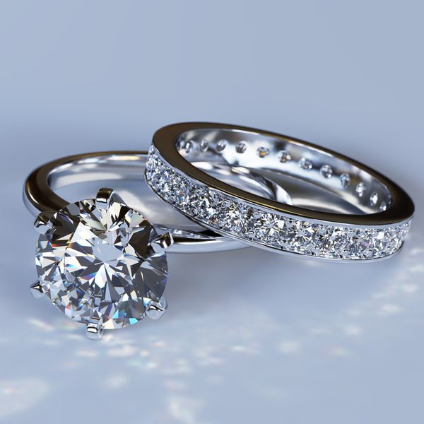 A close-up photo of a diamond engagement ring on a silver band and a diamond pavÃ© wedding band