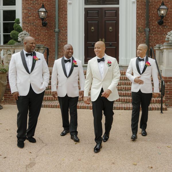 groom and groomsmen wearing tuxedos with white jackets and black pants