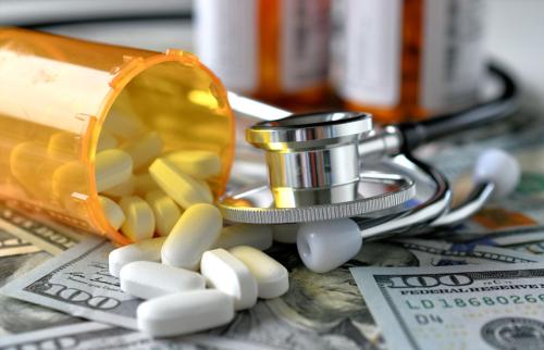 A bottle of medicine and stethoscope on top of $100 bill.