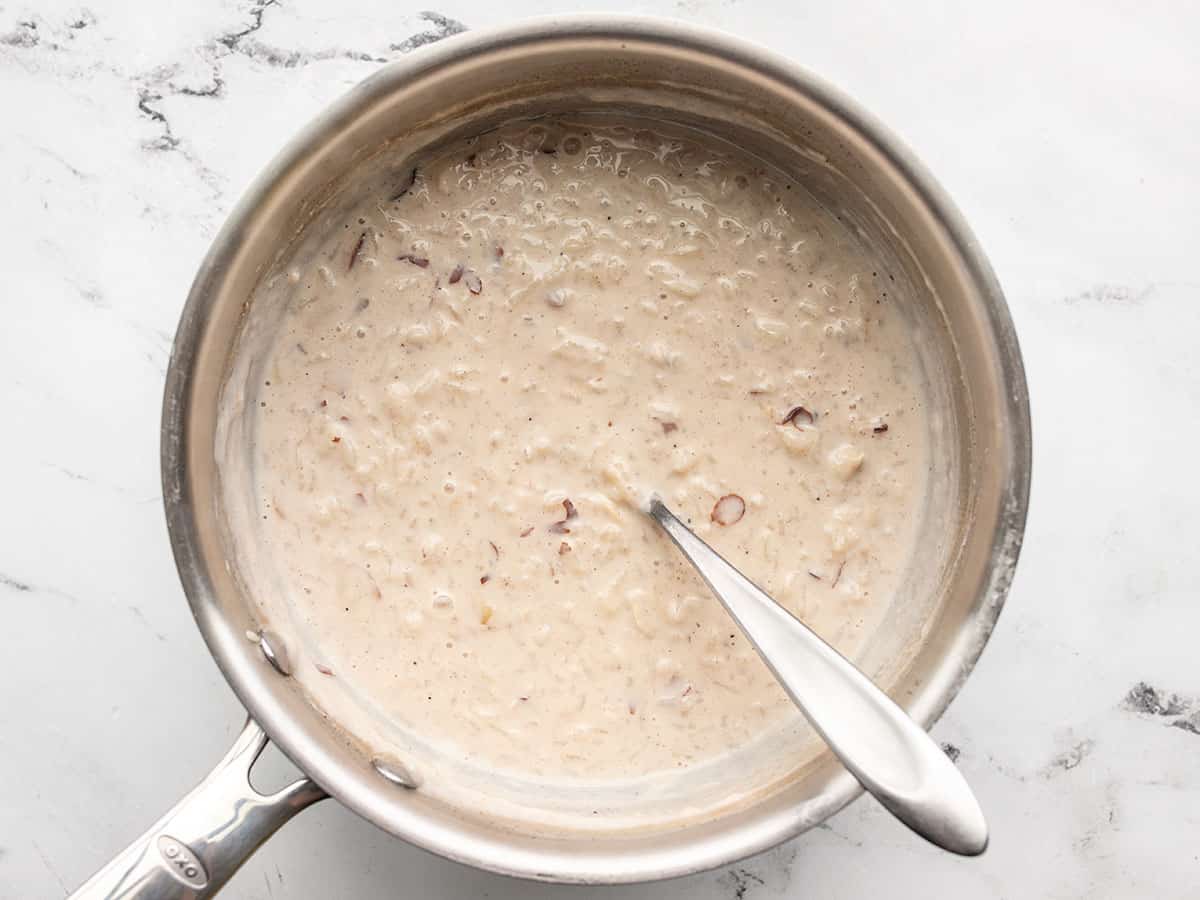 Cooked rice pudding in the pot with a spoon.