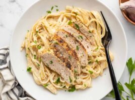 Overhead view of chicken alfredo in a shallow bowl with a fork.