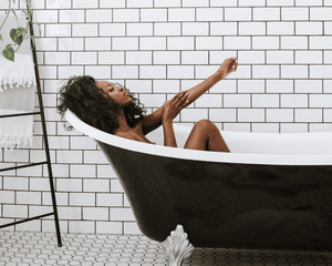 A woman in a claw foot bath tub in a clean, calm bathroom setting