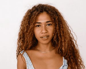 Close up of a model with long, caramel brown curly hair. 