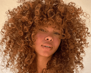 Woman smiling with thick copper curly hair 