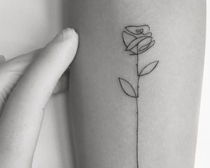 black and white photo of a fine line rose tattoo 