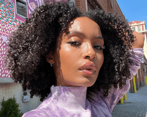 yara shahidi taking a selfie in purple shirt and curly hair