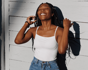 A smiling woman with long hair standing with the sun on her face 