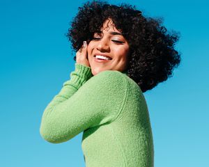 Portrait of a beautiful latina trans woman smiling with confidence with the blue sky behind