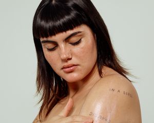 woman applies skincare to her arm, looking down