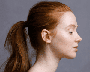 A girl's profile with her red hair in a ponytail