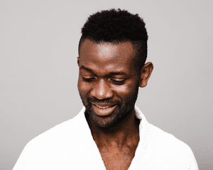 Man smiling and wearing a white bathrobe with shaved sides haircut