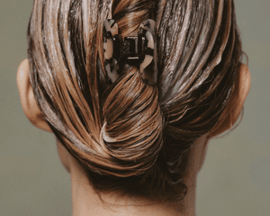 Back of a woman's head with her hair covered in conditioner and clipped up in a twist