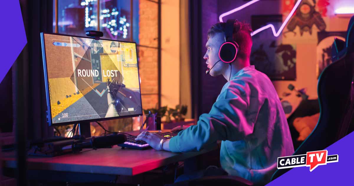 Young man wearing a headset gaming on a desktop computer