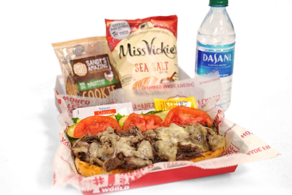 A catering boxed meal from Charleys Cheesesteaks. Charleys boxed meals include your choice of steak, chicken, or veggie cheesesteak, chips, a cookie, and a bottled water. Catered box lunch near me. Cheese steak restaurant near me. Lunch boxes.