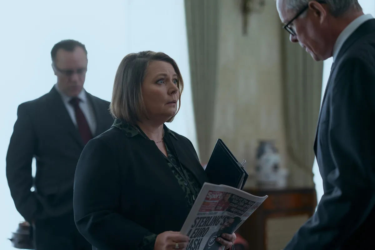 Joanna Scanlan as Amanda Thirsk, holding a newspaper and talking to Sir Edward Young, in 'A Very Royal Scandal'