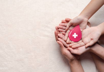 hands holding drop of blood with white cross at the center