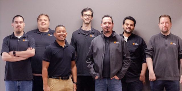 Group photo of CIO Solutions Fresno technical team standing in front of a gray wall